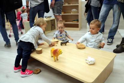 Tres nens que juguen en una taula d'una llar d'infants.