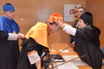 La rectora de la URV, Maria José Figueras, posant el birret al nou doctor honoris causa, Xavier Prats.