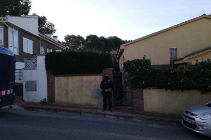 Imagen de un agente delante de uno de los domicilios donde se están haciendo entradas a los Monnars.