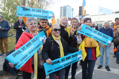 Varios manifestantes con las cartulinas repartidas por el Tsunami Democrático con el lema 'Spain, sit and talk' en torno al Camp Nou