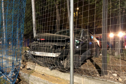 Imatge del cotxe encastat contra un petit mur i la xarxa del camp.