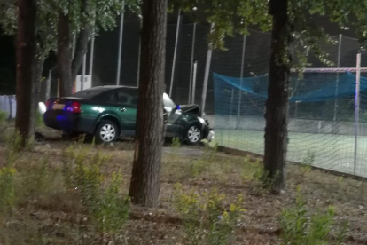 Imagen del coche estampado contra un pequeño muro y la red del campo.