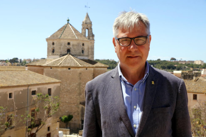 El cap de llista d'ERC i alcalde de Torredembarra, Eduard Rovira, en un terrat de la casa consistorial amb la parròquia de Sant Pere al fons.