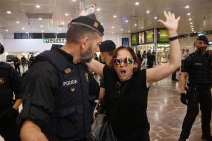 Una manifestante con unas gafas con el símbolo de la paz discute con un agente de los Mossos cuando la desalojan.