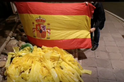 Membres del grup mostren la muntanya de llaços retirats juntament amb una bandera espanyola.