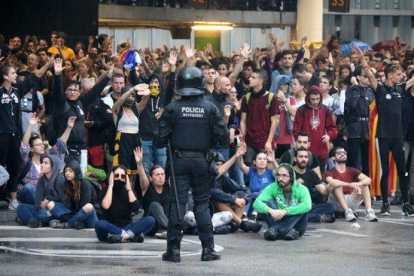 Un grup de manifestants a l'aeroport del Prat convocats per Tsunami Democràtic, darrere d'una línia policial.
