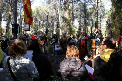 Miembros de Músics per la Independència de Igualada y de un grupo de personas interpretando canciones en el bosque del Catllar.