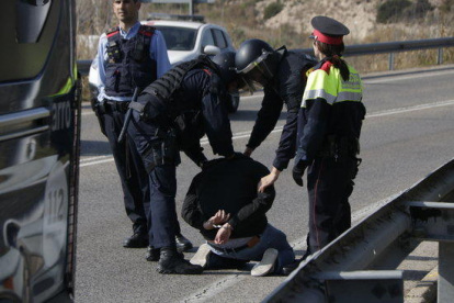 El detenido por los Mossos d'Esquadra, en el suelo, al lado de varios agentes, en el intento de acceso en la AP-7 en Tarragona.