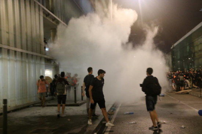 Un grup de manifestants a l'aeroport del Prat convocats per Tsunami Democràtic, enmig de fum.