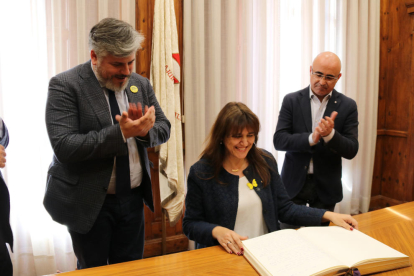 La consellera de Cultura, Laura Borràs, signant el llibre d'honor a l'Ajuntament de Valls, amb l'alcalde de la ciutat, Albert Batet, i el delegat del Govern a Tarragona, Òscar Peris.