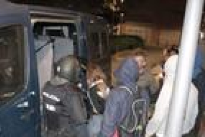 La chica detenida subiendo a la furgoneta de la Policía Nacional, rodeada de agentes, durante los disturbios de esta noche del jueves.