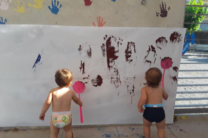 Dos infants pintant en una paret a la llar d'infants del Morell.