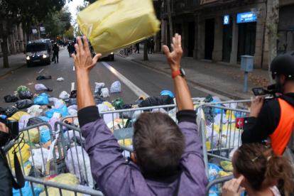 Un home llança una bossa d'escombraries a l'entorn de la delegació del govern espanyol a Barcelona.