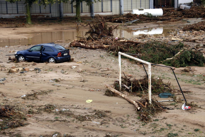 Pla picat d'una zona de Montblanc amb una porteria de futbol, un cotxe malmès i un dipòsit arrossegats entre el fang i els troncs que ha deixat la riuada. Imatge del 23 d'octubre del 2019 (horitzontal)