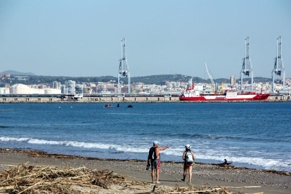 Dues motos aquàtiques i una llanxa fent cerca de desapareguts al mar, entre el port de Tarragona i la platja de la Pineda, plena de canyes i amb dues persones assenyalant a l'horitzó.