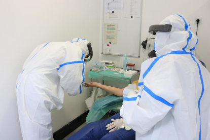 Professionals sanitaris, amb equip de protecció individual (EPI), en el moment d'extreure una mostra de sang amb una punxada al dit a una participant a l'estudi de seroprevalença del coronavirus a nivell estatal.