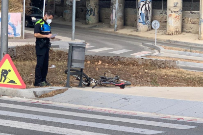 Un agent de la Guàrdia Urbana observant la bicicleta accidentada.
