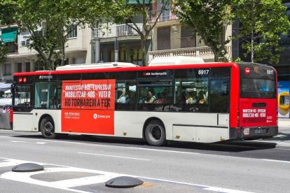 Pla general d'un autobús de TMB amb l'anunci d'Òmnium Cultural.