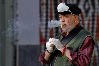 Un home es retira la mascareta per fumar una cigarreta.