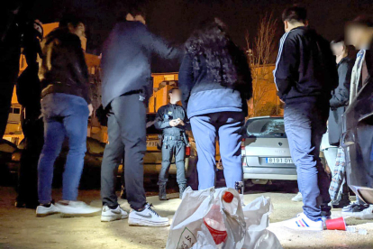 Agents de la Guàrdia Urbana de Reus, de nit, denunciant un grup de joves per consumir alcohol a la via pública.