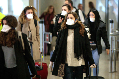 Passatgers d'un avió a un aeroport i que duen màscares.