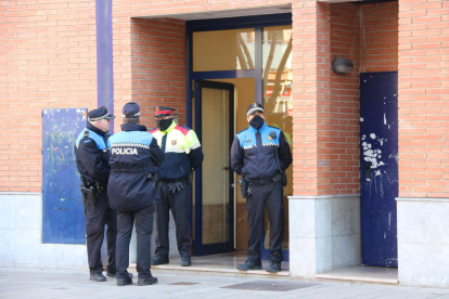 Agents de la Policia Local d'Esplugues de Llobregat i dels Mossos d'Esquadra, a la porta de l'edifici on hi ha el domicili on un home ha estat detingut acusat de matar la seva dona i la seva filla.