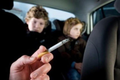 Un conductor fumando con dos niños detrás.