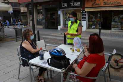 Una educadora informant a dues dones assegudes a una terrassa d'un bar de Reus.