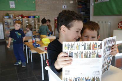 Unos niños mirando un libro de gigantes en la escuela Corazón|Coro de Roble de Santa Coloma de Queralt.