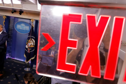 Un cartel con el mensaje 'Exit' (Salida) en primero plan|plano, con la imagen de Trump en uno de los lados, durante un discurso en la Casa Blanca.