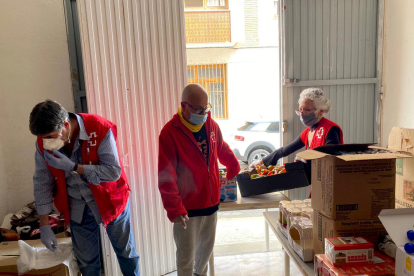 Voluntarios de Cruz Roja de Amposta preparando cajas con productos alimenticios y de higienees para repartir entre las familias más vulnerables de la ciudad.