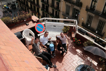 El grup Stay Homas saludant mentre toquen a la terrassa del pis que comparteixen a l'Eixample de Barcelona.