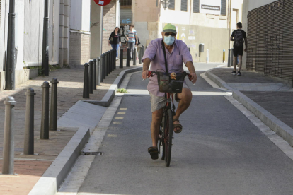 Una persona circula en bicicleta, con la mascarilla puesta, por el centro de Reus.