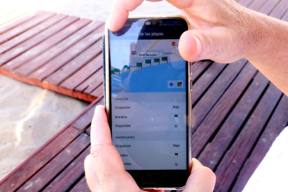 Detall d'un telèfon mòbil amb l'app sobre informació de les platges del Vendrell.