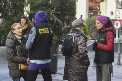 Voluntaris d'Amnistia Internacional dialoguen amb alguns vianants a la plaça Prim.