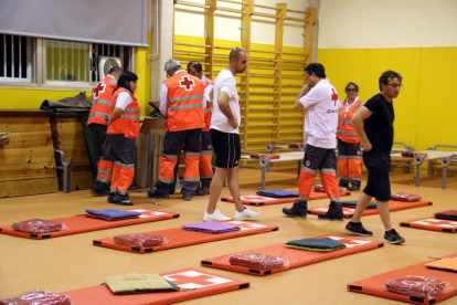 Pla general de l'aula esportiva de l'escola Enric Grau Fontseré de Flix amb els voluntaris de Creu Roja preparant tots els matalassos i mantes per dormir els desallotjats. Imatge del 27 de juny del 2019 (horitzontal)