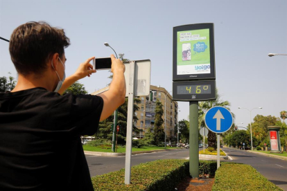 Un joven fotografía un termómetro de calle en Córdoba que marca 46 grados.