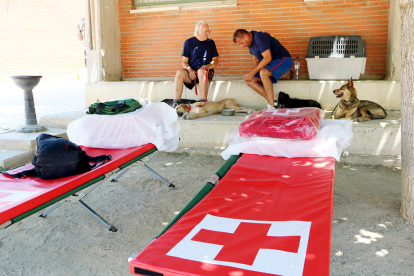 Varias personas desalojadas, en el patio de la escuela de Flix, con varias literas|camillas de la Cruz Roja en primer término.