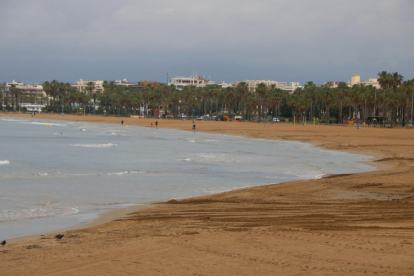 La playa de Llevant de Salou con sólo algunas personas paseando cerca del mar.