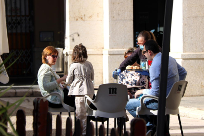 Una família asseguts a la terrassa d'un bar a Tortosa on els serveixen l'esmorzar.