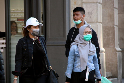 Gente paseando por Barcelona con mascarillas.