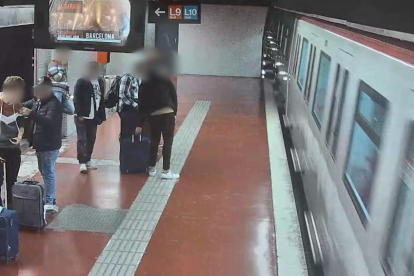 Imatge d'una càmera de seguretat del metro de Barcelona en què es veu a la part esquerra un dels membres de la banda especialitzada en furts que neteja l'escopinada a la víctima mentre una segona persona agafa la maleta del passatger.