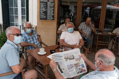 Un grupo de personas mayores utilizando mascarilla en un bar.