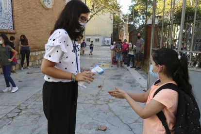 Una docente toma la temperatura y aplica gel a una alumna de la Escola Prat de la Riba de Reus.