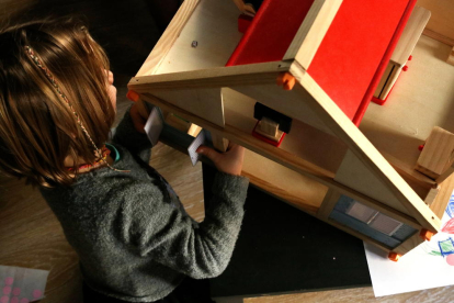 Imatge d'arxiu d'una nena jugant amb una casa de nines.