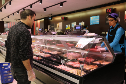 Un cliente con guantes comprando carne en un supermercado del Espai Gironès.