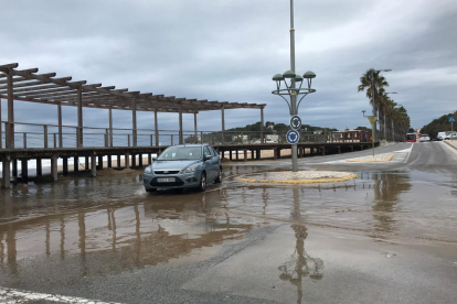 Un cotxe intentant passar per una rotonda amb tolls d'aigua de mar, a la platja de l'Arrabassada de Tarragona, a causa del temporal.