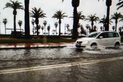Un cotxe circulant pel passeig inundat.
