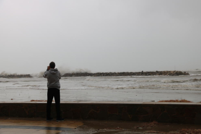 Un home d'esquenes fent una foto a les fortes onades que s'han registrat avui a les platges de Cunit.
