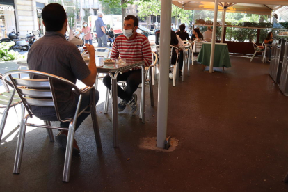 Plano abierto de un grupo de personas sentadas en la terraza de un bar a la la Rambla de Catalunya en el primer día de fase 1 en Barcelona.